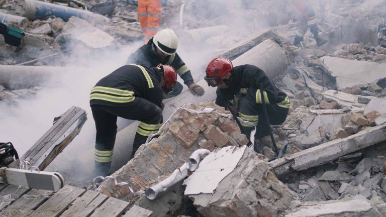 Three rescue workers working in rubble